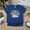 In My Speech Therapist Era text design on a navy blue t-shirt, featuring speech therapy icons like a brain and