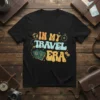 In My Travel Era text graphic on a black t-shirt with passport and compass illustrations