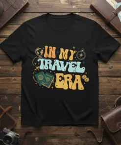 In My Travel Era text graphic on a black t-shirt with passport and compass illustrations