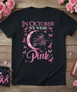 Black t-shirt with "In October We Wear Pink" text, a witch on a broom, moon, and pink ribbons