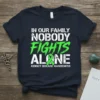 T-shirt with "In Our Family Nobody Fights Alone Kidney Disease Awareness" text and a green ribbon graphic
