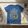 T-shirt with "In this CLASSROOM Everyone WELCOME" text, rainbow hearts, and diverse hands raised, promoting classroom inclusion
