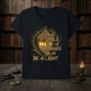 Inspirational quote "In A World Full Of Darkness Be A Light" with a glowing lantern graphic on a dark t-shirt