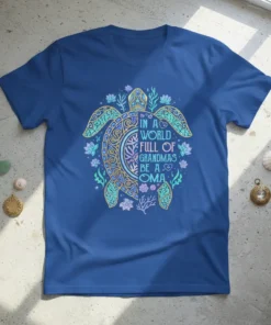 T-shirt with "In A World Full Of Grandmas Be A Oma" text inside a decorative sea turtle design, surrounded by