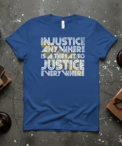 Blue t-shirt with white text reading "INJUSTICE ANYWHERE IS A THREAT TO JUSTICE EVERY WHERE" in a bold, stylized font