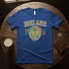 Blue t-shirt with "IRELAND" text above a Claddagh crest featuring hands, heart, shamrock, crown, and Celtic knots