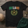 Black t-shirt with "IRELAND" text in green, white, and orange, featuring a distressed soccer ball within a Celtic knot design