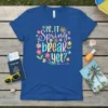 Is It Spring Break Yet? text design with flowers, sun, butterflies, and an arrow on a blue t-shirt