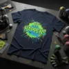 Navy blue t-shirt with "IT HAPPENS" in bold green and blue lettering surrounded by colorful paint splatters