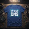Blue t-shirt with white text "IT WAS DNS" in a circuit board design, for tech humor and IT jokes