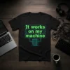 Black t-shirt with neon green text "It works on my machine" and server rack graphic, suitable for tech humor