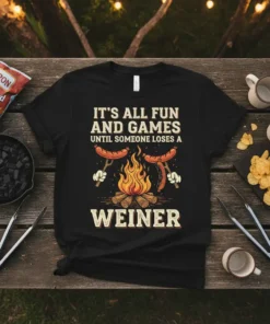 Black t-shirt with "IT'S ALL FUN AND GAMES UNTIL SOMEONE LOSES A WEINER" text, featuring hot dogs on forks over