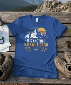 T-shirt featuring the quote "It's Another Half Mile Or So" with a mountain sunset graphic and footprints, designed for hikers