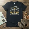 It's Another Half A Mile Or So... text design with mountains and sun graphic on a black t-shirt