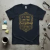 Dark t-shirt with gold text "IT'S FINE I'M FINE Everything IS FINE" in a decorative frame