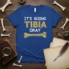 It's Going Tibia Okay funny medical pun t-shirt with a bone graphic and distressed typography