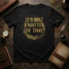 Black t-shirt with gold "IT'S JUST A MATTER OF TIME" text surrounded by gears and steampunk elements
