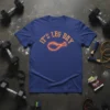 Blue t-shirt with orange neon text "IT'S LEG DAY" and a glowing chicken leg graphic, fitness theme
