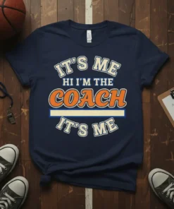 It's Me Hi I'm The Coach It's Me text design on a navy t-shirt, featuring bold orange and cream lettering