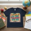 Teacher quote "IT'S ME HI I'M THE TEACHER IT'S ME" in retro font inside an open book graphic, navy t-shirt