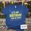Blue t-shirt with bright yellow and pink text that reads "IT'S MY BIRTHDAY SIGN MY SHIRT", surrounded by birthday graphics