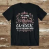 Black t-shirt with "IT'S MY Birthday Week YES I GET THE WHOLE WEEK" text in rose gold and white, featuring