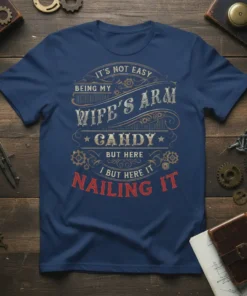 Navy blue t-shirt with vintage distressed text: "It's Not Easy Being My Wife's Arm Candy But Here I But Here