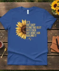 Blue t-shirt with gold text: "It's Not Easy Being The Best Wife Ever But Here I Am Nailing It" and