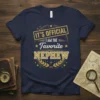 It's Official I Am The Favorite Nephew text design on a navy blue t-shirt, featuring gold and white typography and