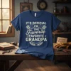 Blue t-shirt with white text that reads "IT'S OFFICIAL I'M THE FAVORITE FAVORITE GRANDPA" and includes engine piston graphics