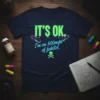 IT'S OK. I'm on 500mgs of fukitol. funny t-shirt with neon green and blue text and skull graphic