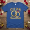Blue t-shirt with gold text "IT'S OUR Anniversary" and intertwined gold rings with a ruby gemstone