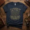 Navy t-shirt with gold vintage-style text "It's A Beautiful Day To Mind Your Own Business" and ornate clock graphic