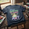 T-shirt with colorful text reading "It's A Good Day To Make Some Art" and an artist's palette graphic