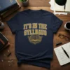 It's In The Syllbaus text with an open book and gears graphic on a navy blue t-shirt