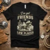 I've Got Friends in Low Places text with cowboy dachshund and western landscape graphic on black t-shirt