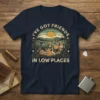 T-shirt design with the quote "I've Got Friends in Low Places" featuring basset hounds and corgis in a scenic landscape