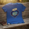 Blue t-shirt with "Jesus Heals" text inside a broken heart graphic and a golden halo above
