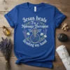 Blue t-shirt with white text "Jesus heals I'm a Massage Therapist Sending my hand" and a cross graphic with floral
