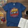 Jesus Is My Superhero t-shirt with bold comic book style text and a stylized 'J' emblem