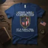 Blue t-shirt with "Jesus Was Convicted Of A Sham Trial I Still Follow Him" text, featuring a shield with the