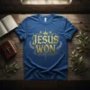 Gold "Jesus Won" text with crown and laurel wreath graphic on a royal blue t-shirt