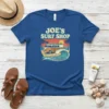 Joe's Surf Shop text with a vintage camper van, palm trees, a sunset, and ocean waves graphic on a blue
