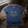 Navy blue t-shirt with golden text "JUDGING YOU SILENTLY." and golden cat eyes graphic