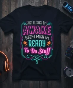 Black t-shirt with neon-style text reading "JUST BECAUSE I'M AWAKE DOESN'T MEAN I'M READY To Do Stuff"