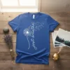 White 'just breathe' text on a blue t-shirt with a dandelion graphic releasing seeds and butterflies