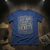 Blue t-shirt with gold lettering that reads "Just Here Because I Bought The Tickets" in ornate font, includes musical notes