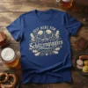 Blue t-shirt with "JUST HERE FOR Schitzengiggles" text and crossed beer mugs graphic, oak leaves, and ornate border
