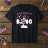 Black t-shirt with white text "JUST HERE TO BANG" and a red, white, and blue rocket launching with fireworks