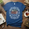 Just One More Chapter quote on a blue t-shirt with a stack of vintage books illustration surrounded by floral design